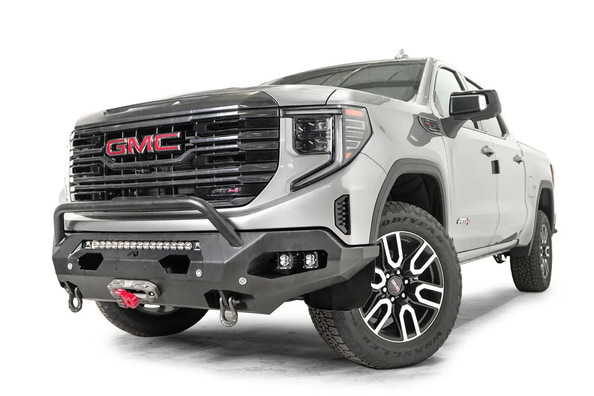 Fab Fours Matrix front bumper with pre-runner guard on a silver GMC Sierra 1500, driver-side front three-quarter view, showing the pre-runner bar, pod light cutouts and D-ring shackle mounts