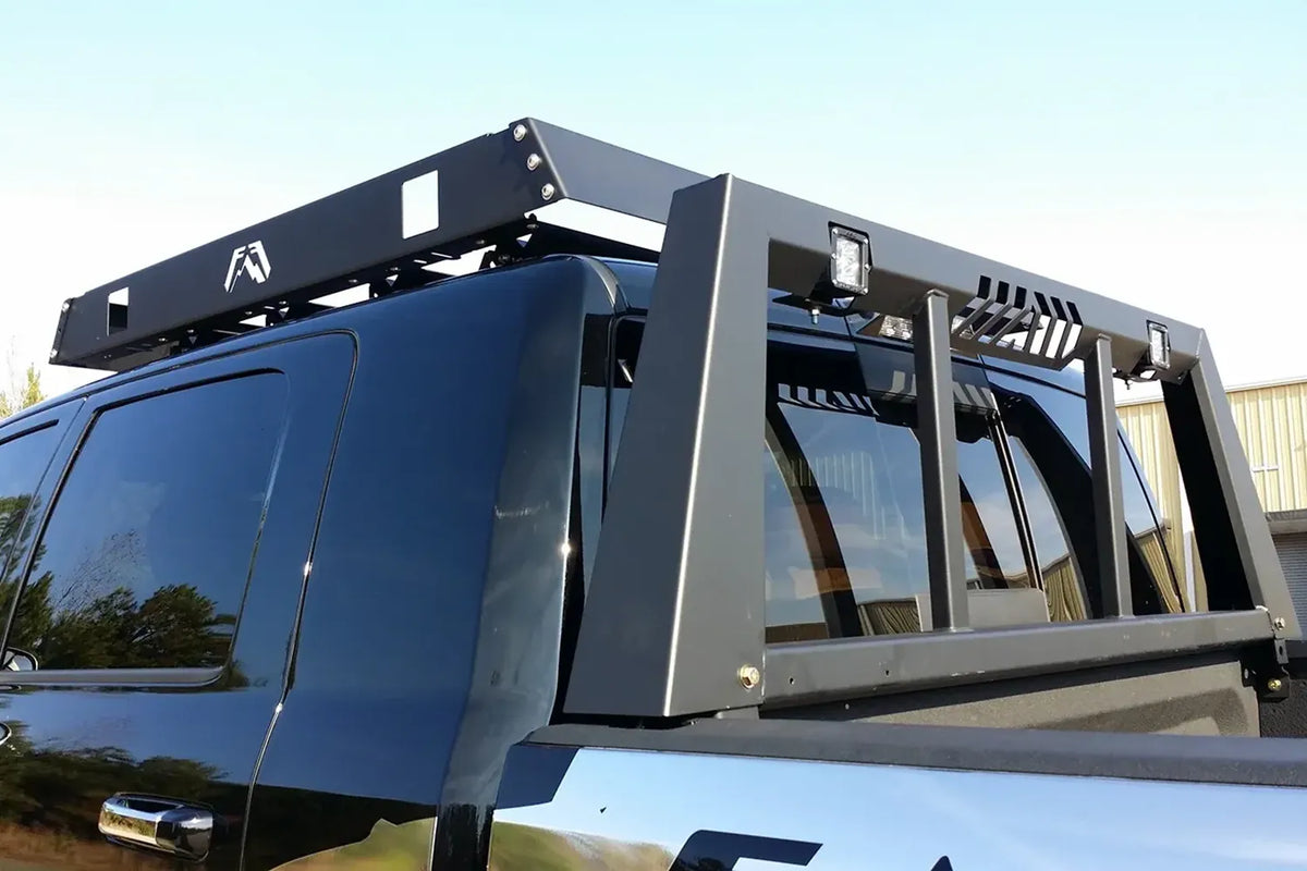 Fab Fours headache rack on a black Ram pickup, close-up outdoors, showing the rack with roof basket, pod lights and slotted top rail vents