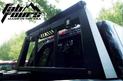 Fab Fours headache rack on a black Ram pickup, close-up outdoors, showing the tapered side post, window bars and top-mounted light bar with pod lights