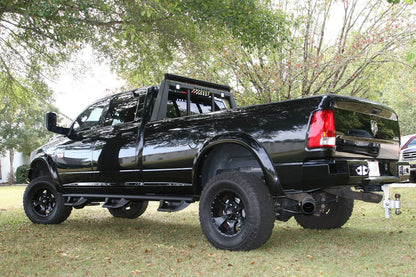 Fab Fours headache rack on a black Ram pickup, rear driver-side three-quarter view outdoors, showing the rack behind the cab with top-mounted lights