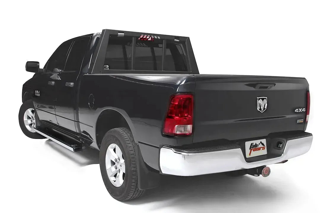 Fab Fours headache rack on a black Ram 1500, rear driver-side three-quarter view, showing the rack behind the cab with tapered side posts and window bars