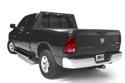 Fab Fours headache rack on a black Ram 1500, rear driver-side three-quarter view, showing the rack behind the cab with tapered side posts and window bars