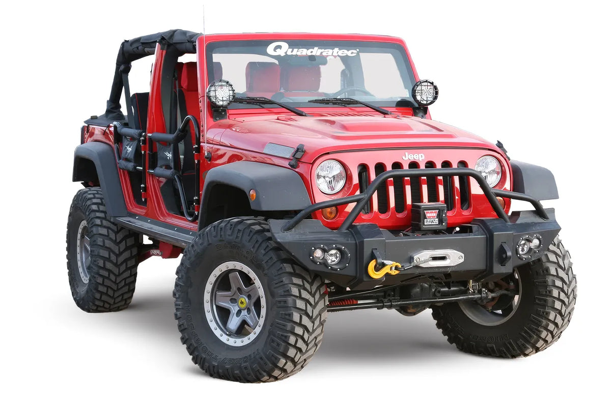 Fab Fours Lifestyle Winch bumper with pre-runner guard on a black Jeep Wrangler JK, front view outdoors, showing the pre-runner hoop, winch mount and fog light openings