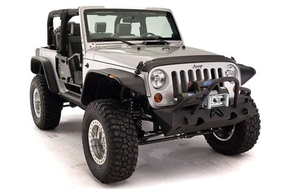 Fab Fours Hardcore Stubby Winch bumper with pre-runner guard on a silver Jeep Wrangler JK, passenger-side front three-quarter studio view, showing the pre-runner hoop, winch mount and stubby end caps