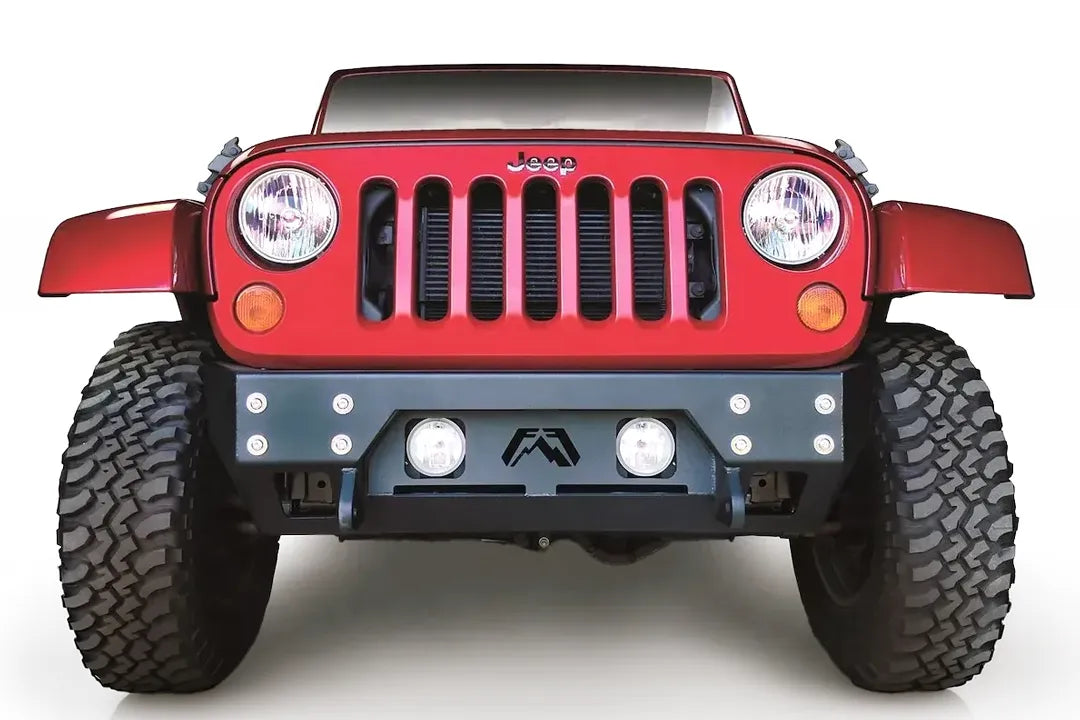 Fab Fours Full Metal Jacket stubby front bumper on a red Jeep Wrangler JK, straight-on front view, showing the bolted face plate, round fog lights and Fab Fours logo cutout