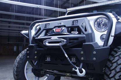 Fab Fours FMJ winch modifier installed on a white Jeep Wrangler JK with Warn winch, synthetic winch line, and cube lights, driver-side front angle