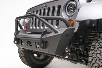 Fab Fours Stubby bumper with pre-runner guard on a silver Jeep Wrangler JK, close-up of the front corner, showing the pre-runner hoop, Fab Fours logo cutout and fog light opening