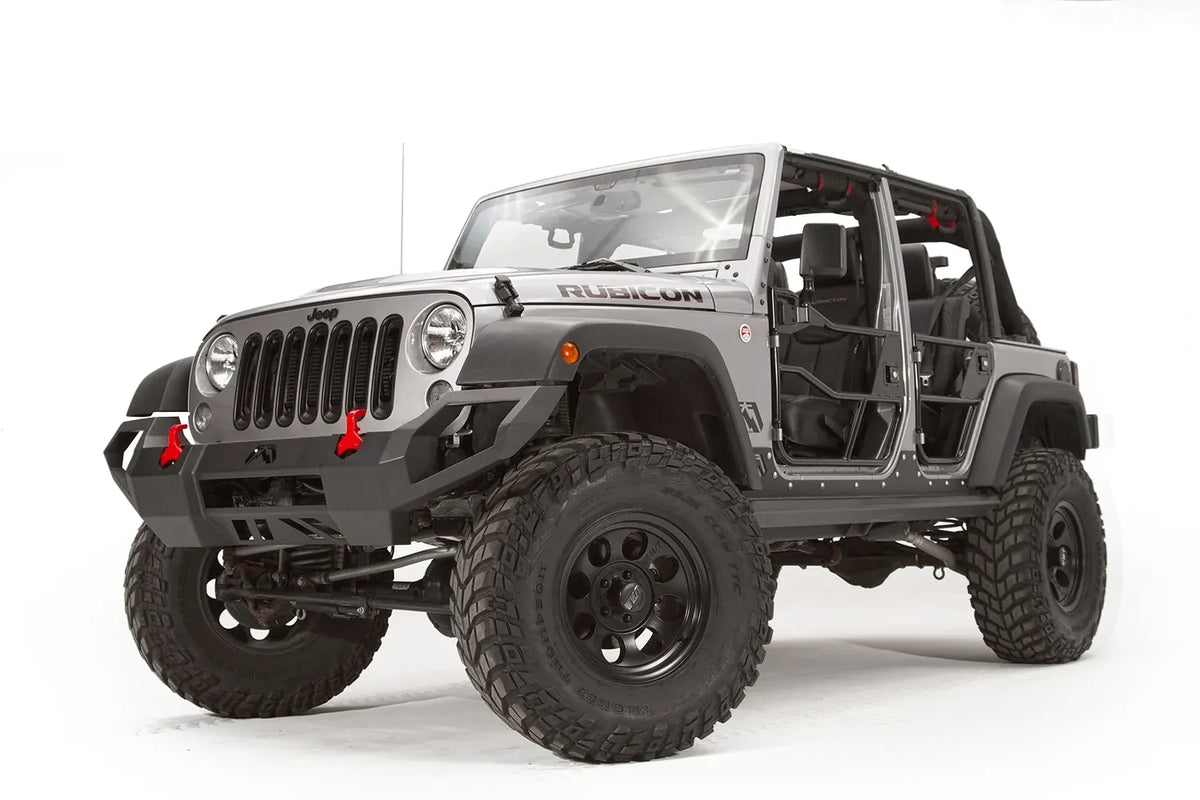 Fab Fours Vengeance front bumper on a silver Jeep Wrangler JK Rubicon, driver-side front three-quarter view, showing the angular bumper face, red shackles and pod light cutouts