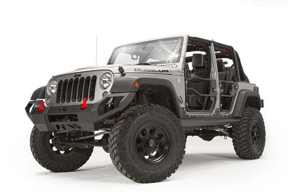 Fab Fours Vengeance front bumper on a silver Jeep Wrangler JK Rubicon, driver-side front three-quarter view, showing the angular bumper face, red shackles and pod light cutouts