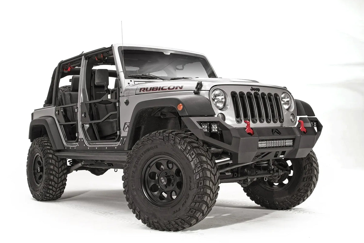 Fab Fours Vengeance front bumper on a silver Jeep Wrangler JK Rubicon, passenger-side front three-quarter view, showing the angular bumper face, center light bar and red shackles