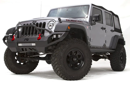 Fab Fours Vengeance front bumper with pre-runner guard on a silver Jeep Wrangler JK Rubicon, driver-side front three-quarter view, showing the pre-runner hoop, center light bar and pod lights