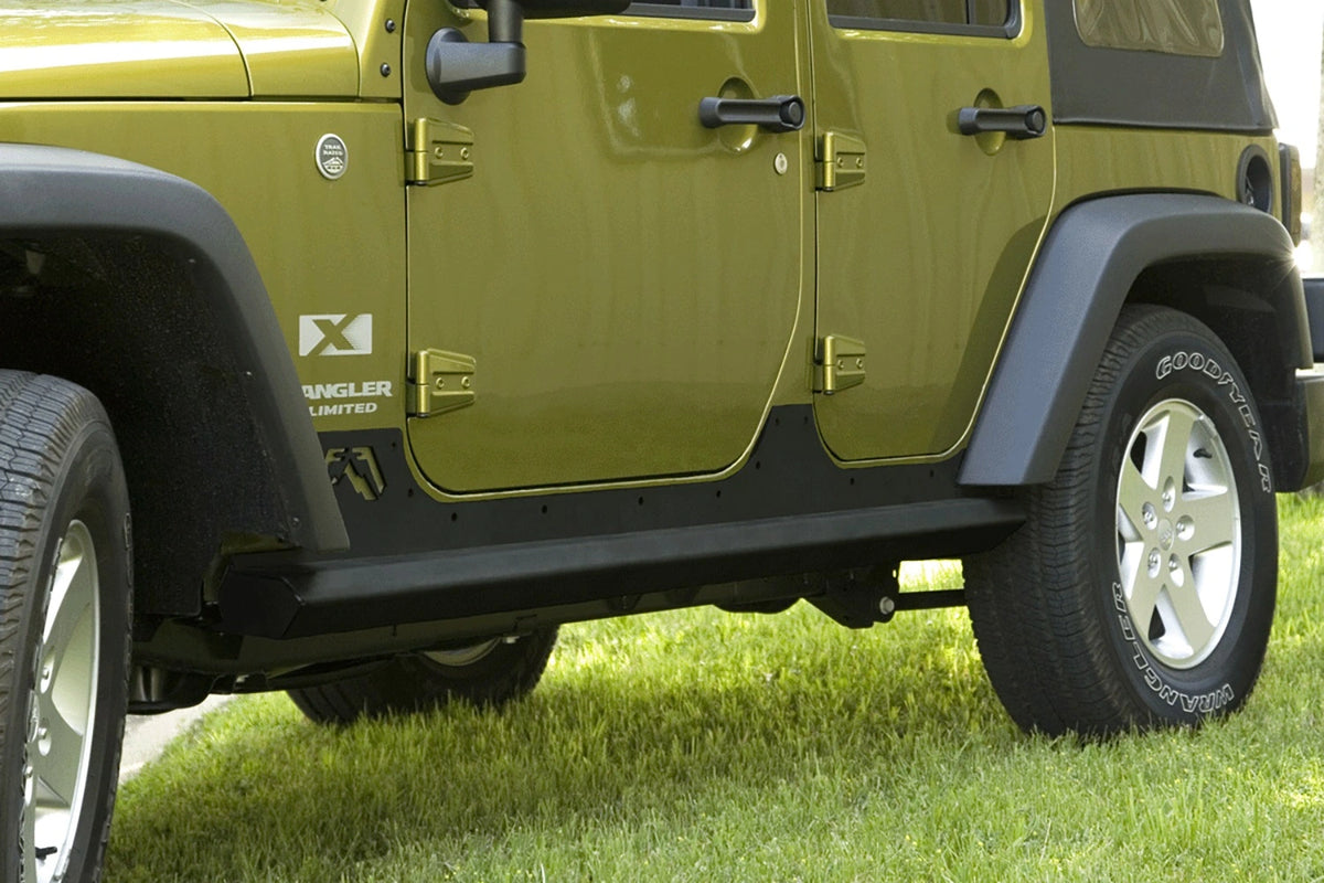 Fab Fours HardCore Rock Sliders on a green Jeep Wrangler JK Unlimited, driver-side view outdoors, showing the slider rail along the rocker and riveted rocker plate