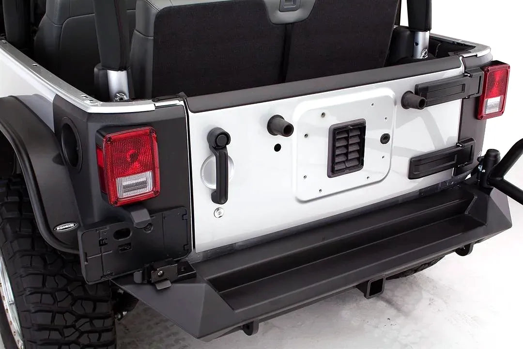 Close-up of Fab Fours heavy-duty rear bumper on a silver Jeep Wrangler JK, showing the step surface, hitch receiver, and tire carrier mount