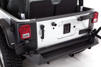 Close-up of Fab Fours heavy-duty rear bumper on a silver Jeep Wrangler JK, showing the step surface, hitch receiver, and tire carrier mount