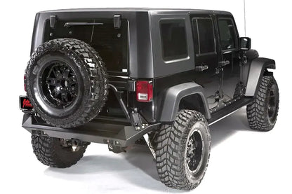 Fab Fours heavy-duty rear bumper with tire carrier and spare tire on a lifted black Jeep Wrangler JK Unlimited, passenger-side rear three-quarter view