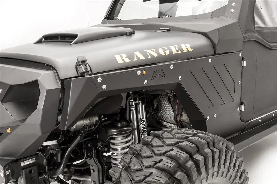 Close-up of Fab Fours front steel fender with vent pattern and Fab Fours logo on the driver side of a black Jeep Wrangler JK, with Fox shocks visible