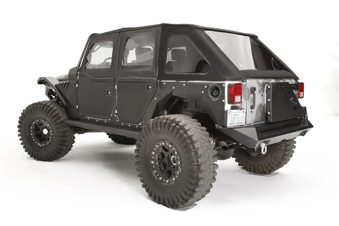 Fab Fours rear fender base on a black 4-door Jeep Wrangler JK, rear driver-side three-quarter view, showing the riveted rear fender panel, exposed wheel well and fuel door cutout