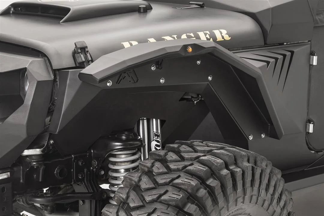 Fab Fours front inner fender and fender flare with amber marker light on the driver side of a black Jeep Wrangler JK, with Fab Fours logo cutout and Fox shock visible