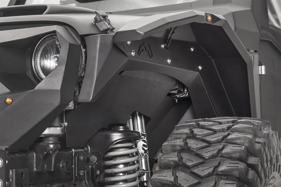 Fab Fours front inner fender and fender flare on the driver side of a black Jeep Wrangler JK, next to the headlight, with amber marker light and Fab Fours logo cutout
