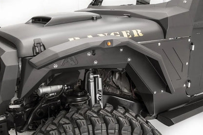 Fab Fours aggressive narrow front fender flare on a black Jeep Wrangler JK, driver-side close-up, showing the faceted steel flare with marker light, Fab Fours logo, inner fender liner and coilover shocks