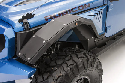 Fab Fours full-width front fender flare on a blue Jeep Wrangler JL Rubicon, driver-side close-up, showing the faceted black steel flare with button-head bolts, Fab Fours logo, marker light and inner fender liner