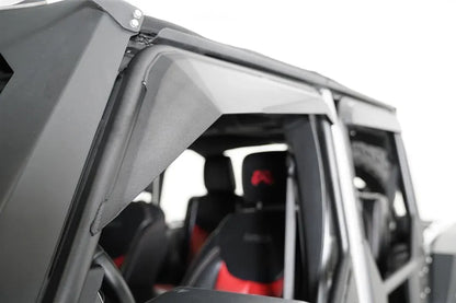 Fab Fours full tube door on a Jeep Wrangler JK, close-up of the padded upper window frame, showing the angled black cover over the tube with the interior and seats behind