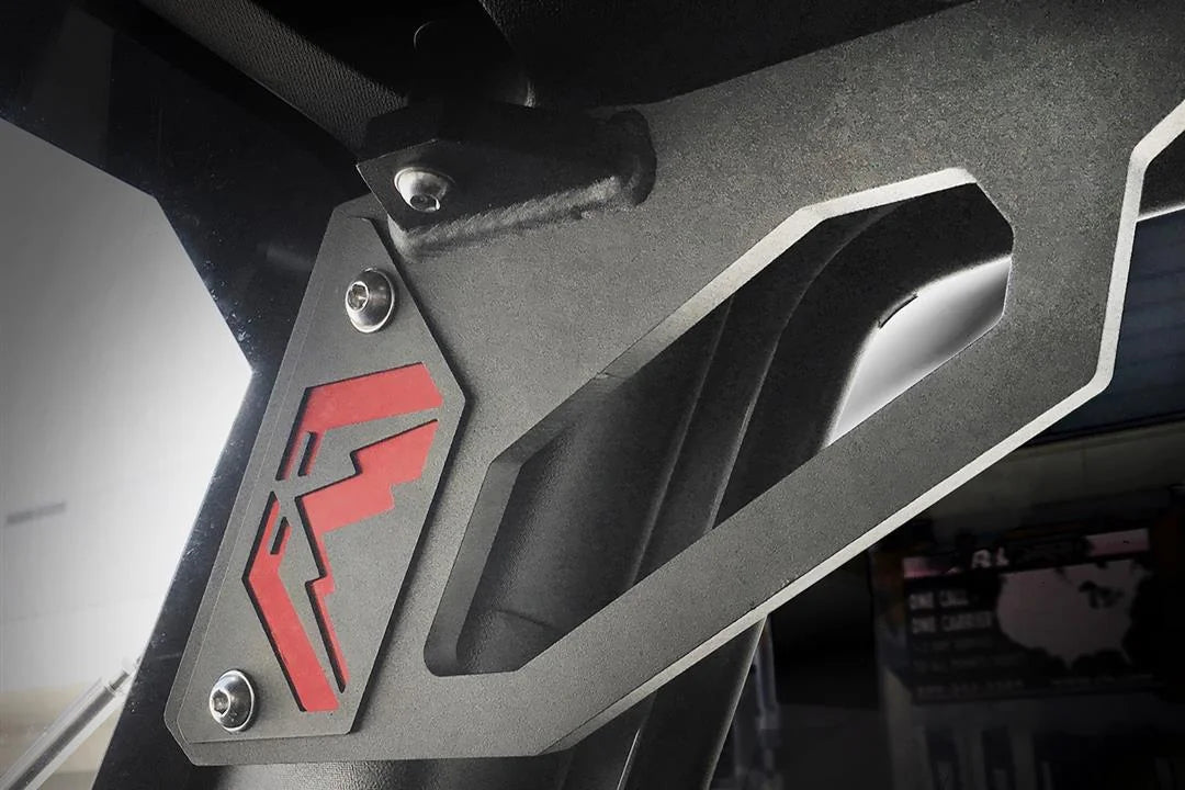 Fab Fours grab handle on a Jeep Wrangler JK, low-angle close-up, showing the open grip cut-out, the red Fab Fours logo inlay and the bolted mount at the windshield frame