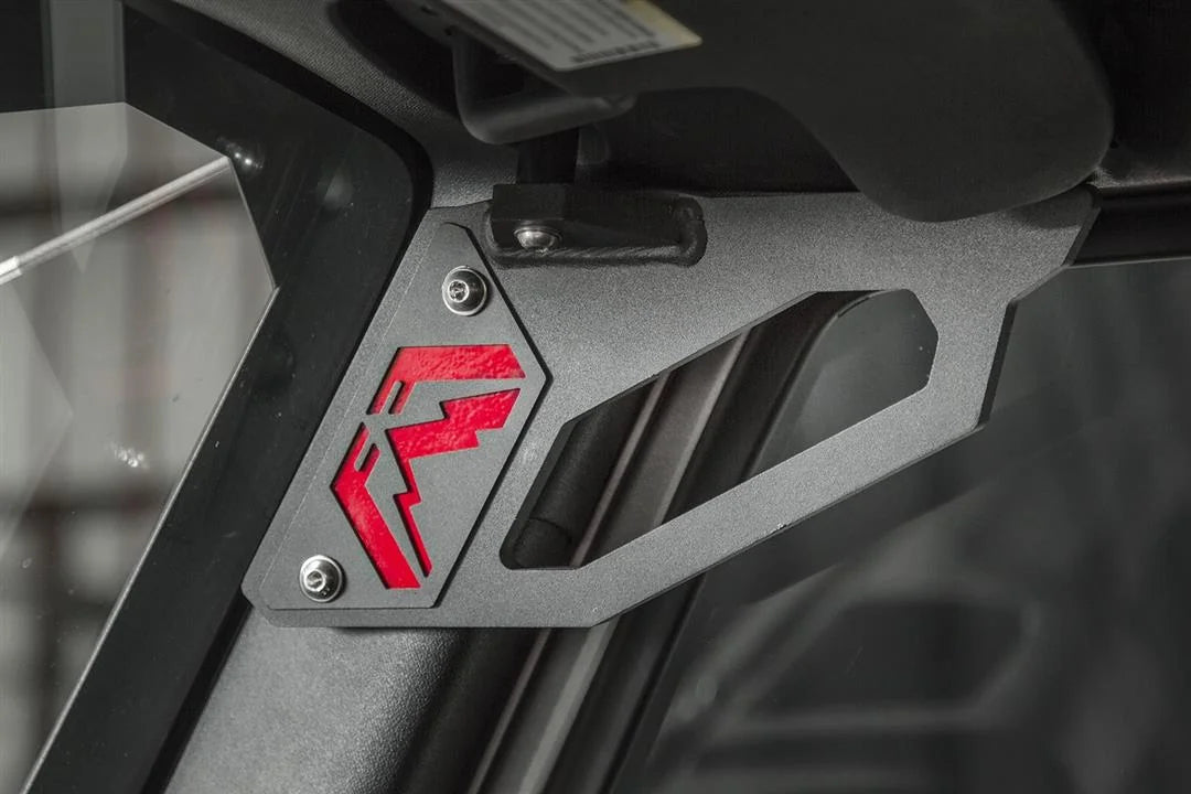 Fab Fours grab handle mounted to the windshield frame of a Jeep Wrangler JK, close-up, showing the black cut-out handle with the red Fab Fours logo insert and button-head bolts