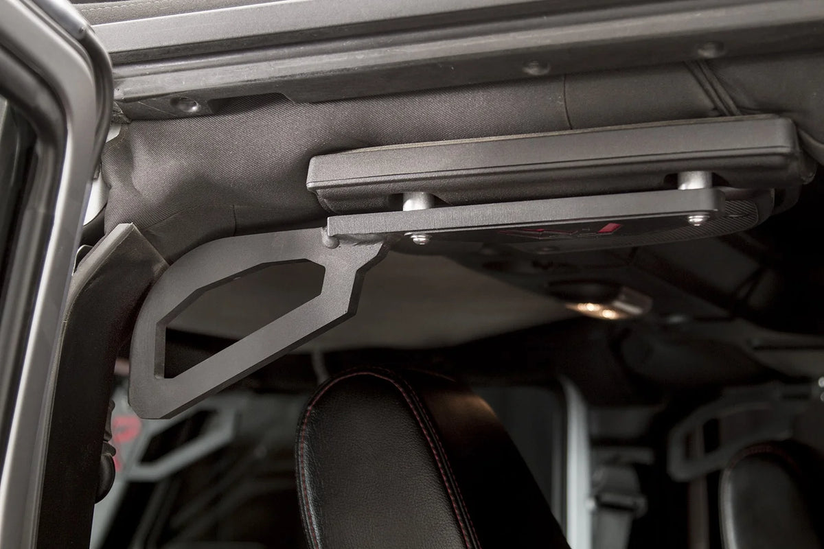 Side view of the Fab Fours grab handle mounted to the roll bar of a Jeep Wrangler JK, showing the angular steel grip and bolted bracket above the front seat
