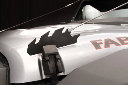Fab Fours limb riser on a silver Jeep Wrangler, close-up of the black steel bracket with its sawtooth profile, mounted over the factory hood latch, with the cable attached at the rear tooth