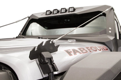 Fab Fours limb riser on a silver Jeep Wrangler, close-up of the jagged black steel bracket mounted at the hood latch, with the steel cable running up to the Fab Fours windshield frame