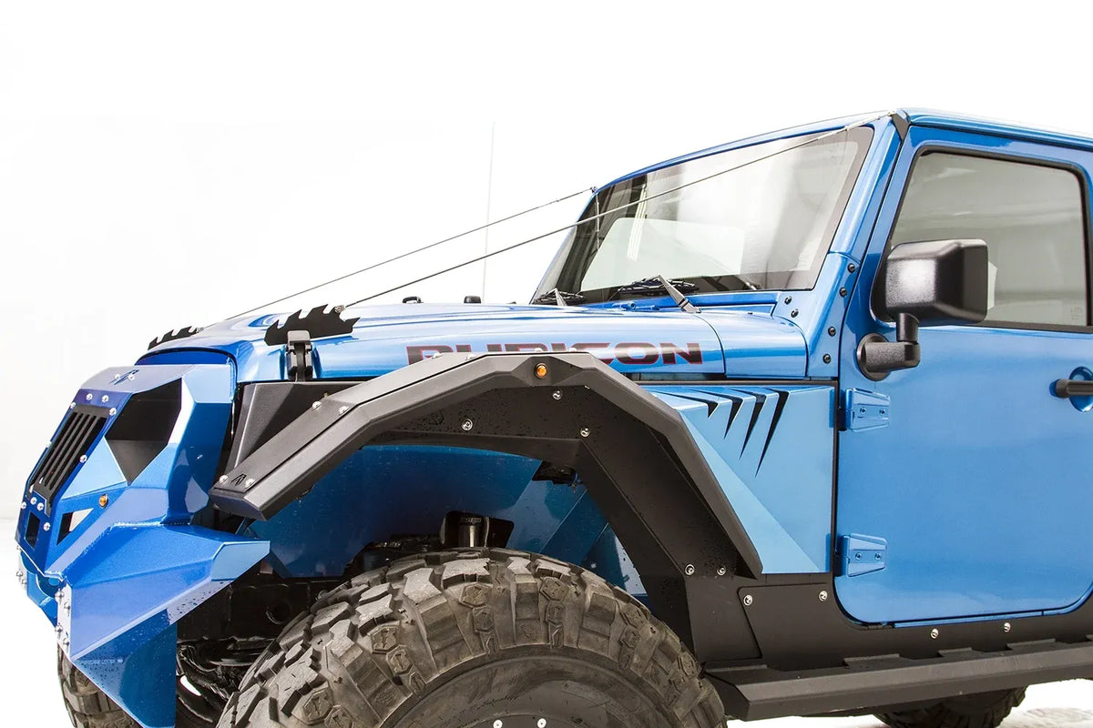 Fab Fours limb riser on a lifted blue Jeep Wrangler JK Rubicon, driver-side view, with cables running from the hood to the windshield above matching Fab Fours fender flares