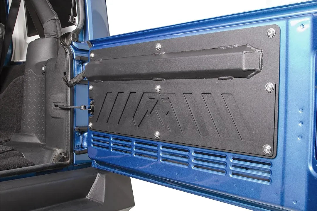 Fab Fours tailgate plate on a blue Jeep Wrangler JK, angled close-up, showing the welded storage tube, button-head bolts and the stamped Fab Fours logo above the tailgate vents