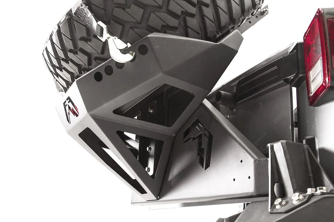 Close-up of the Fab Fours Slant Back Tire Carrier, showing the faceted steel frame, Fab Fours logo cutouts and strap hook