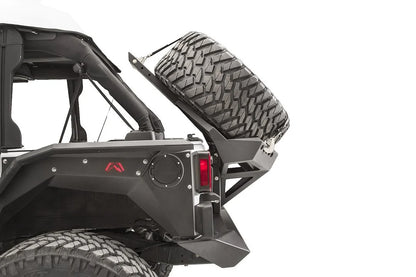 Close-up of the Fab Fours Slant Back Tire Carrier on a Jeep Wrangler JK, rear driver-side view, showing the angled carrier arm holding the spare at a slant
