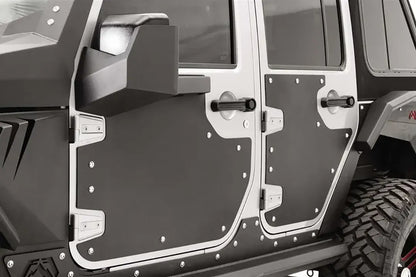 Fab Fours door skins on the front and rear doors of a Jeep Wrangler JK Unlimited, close-up from the driver side, showing the black riveted panels inside the silver door frames with the mirror mount on the front door