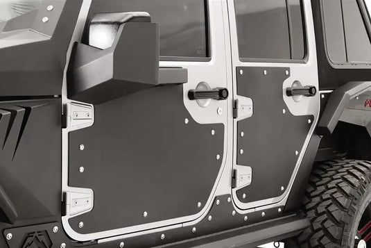 Fab Fours door skins on the front and rear doors of a Jeep Wrangler JK Unlimited, close-up from the driver side, showing the black riveted panels inside the silver door frames with the mirror mount on the front door