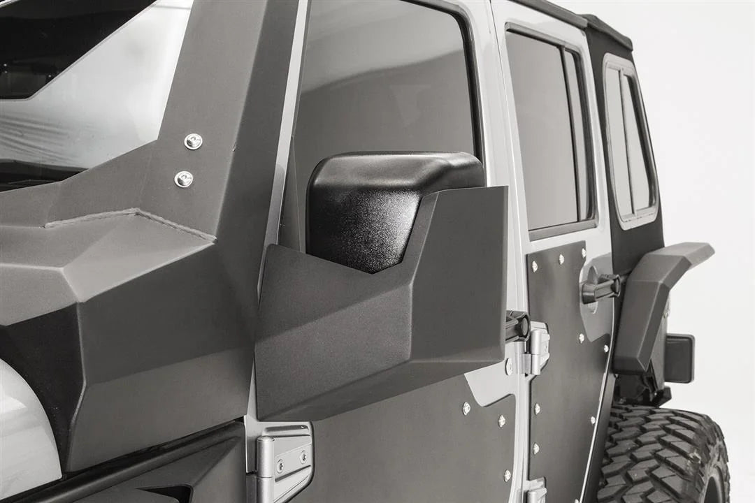 Fab Fours door skin mirror guard on a Jeep Wrangler JK, driver side, showing the faceted mirror housing on the steel door skin beside the cowl armor