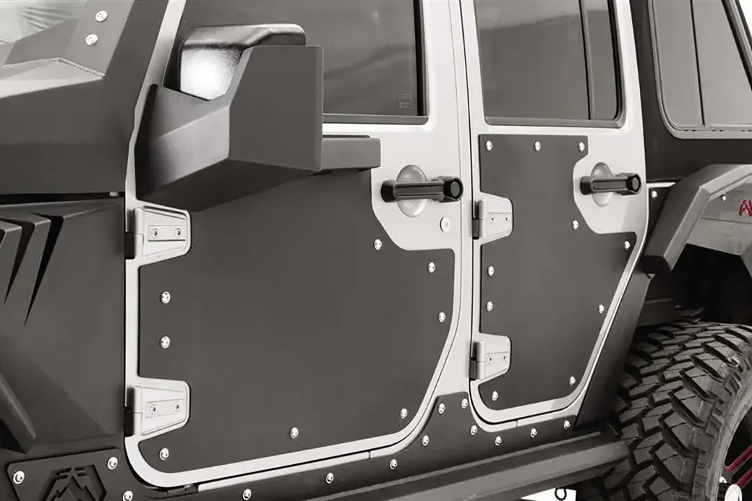 Close-up of Fab Fours door skins on a silver Jeep Wrangler JK, driver side, showing the matte black steel panels bolted around the door handles and hinges with stainless hardware