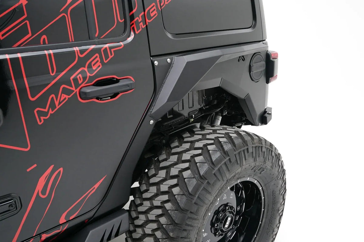 Close-up of Fab Fours rear steel fender with Fab Fours logo around the fuel door on the driver side of a black Jeep Wrangler JL with red Fab Fours graphics