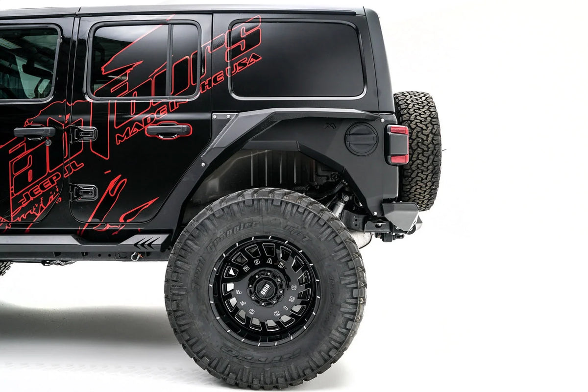 Fab Fours rear steel fender with Fab Fours logo around the fuel door on a lifted black Jeep Wrangler JL, driver-side view of the rear wheel