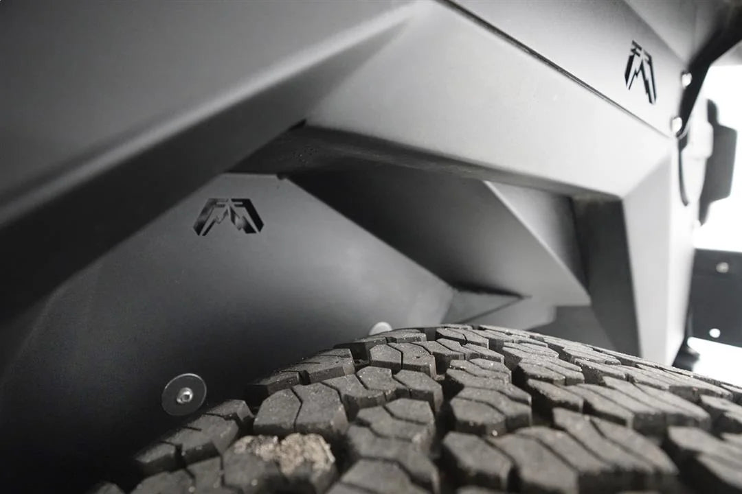 Close-up of Fab Fours inner fender liner inside the rear wheel well of a Jeep Wrangler JL, with Fab Fours logo cutouts above the tire