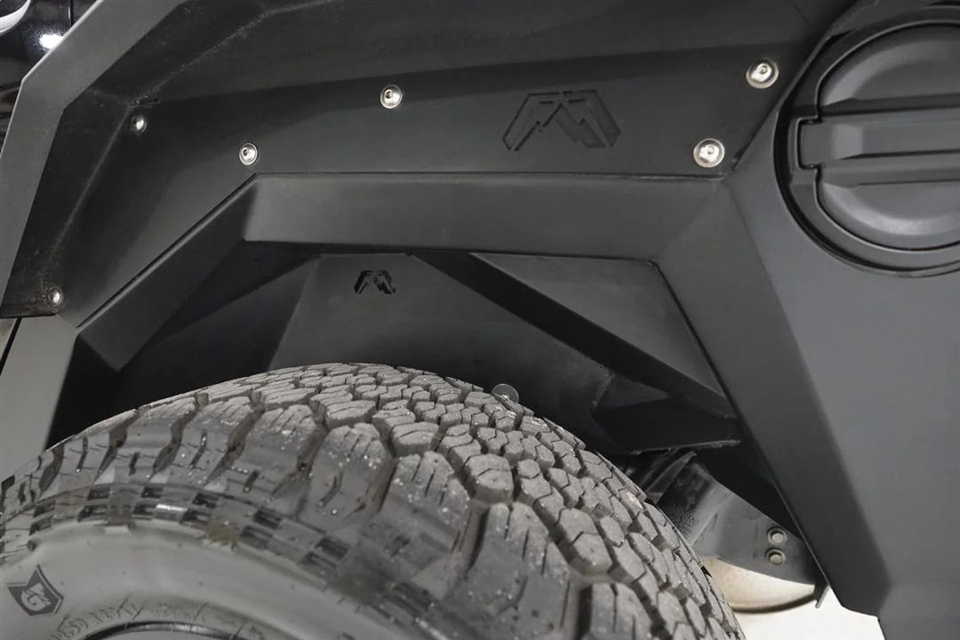 Fab Fours inner fender and fender flare in the driver-side rear wheel well of a black Jeep Wrangler JL, with Fab Fours logo cutouts