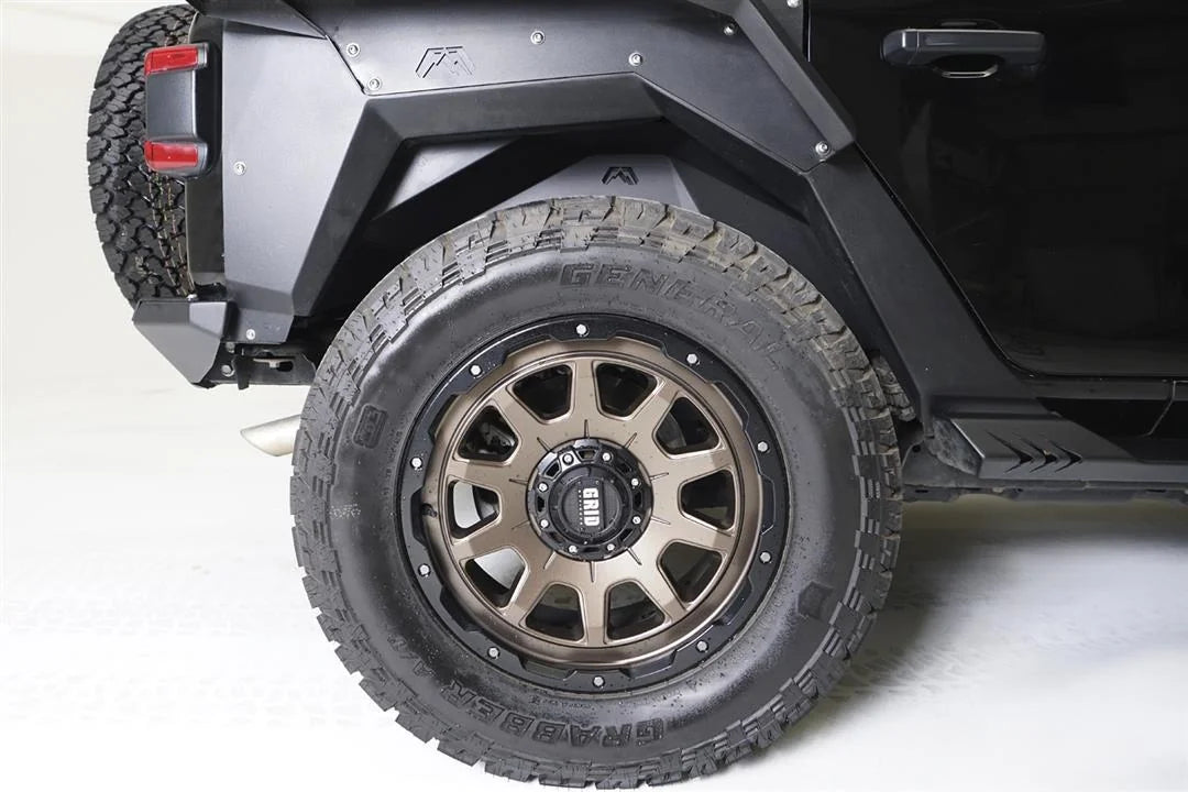 Fab Fours inner fender and fender flare on the passenger-side rear wheel of a black Jeep Wrangler JL, with bronze wheel and all-terrain tire