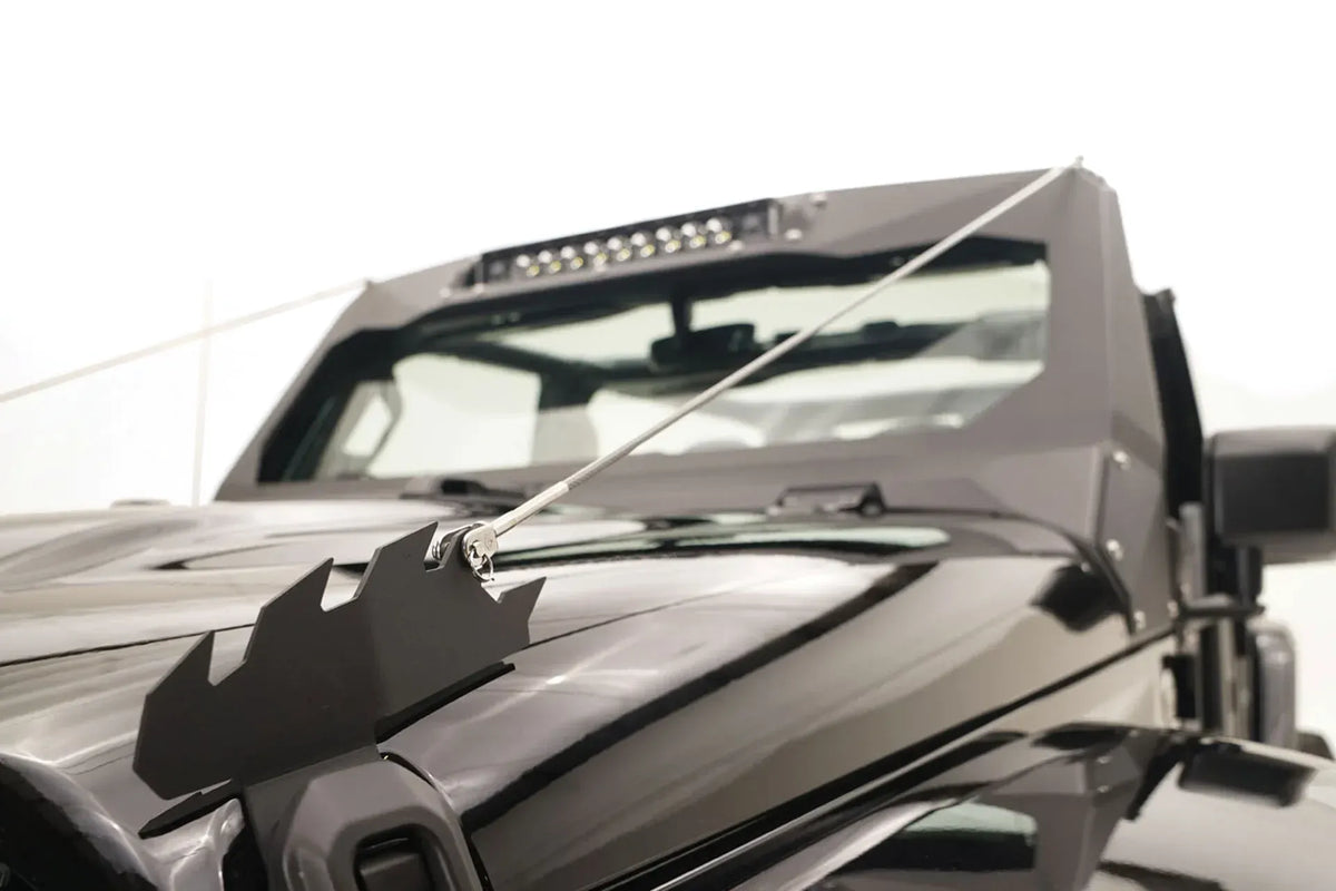 Fab Fours ViCowl Limb Riser on a black Jeep Wrangler JL, close-up of the steel hood anchor bracket with stainless cable running up to the windshield cowl