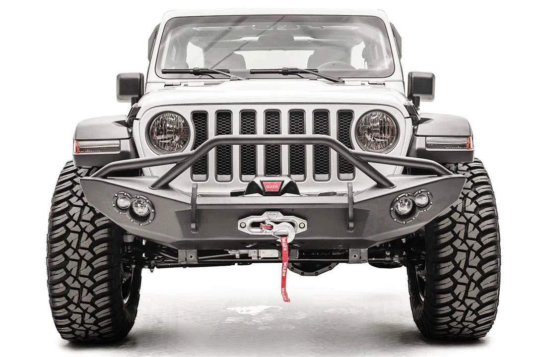 Fab Fours Lifestyle winch bumper with pre-runner guard on a white Jeep Wrangler JL, straight-on front view, showing the tube hoop, centered winch and round light pods