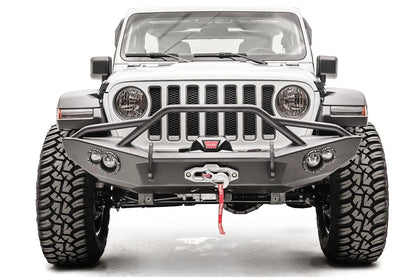 Fab Fours Lifestyle winch bumper with pre-runner guard on a white Jeep Wrangler JL, straight-on front view, showing the tube hoop, centered winch and round light pods