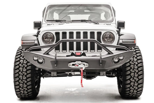 Fab Fours Lifestyle winch bumper with pre-runner guard on a white Jeep Wrangler JL, straight-on front view, showing the tube hoop, centered winch and round light pods