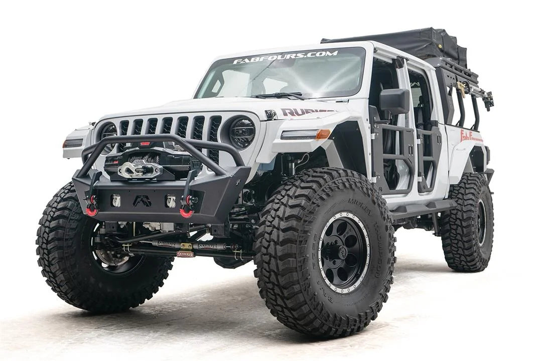 Fab Fours Stubby bumper with pre-runner guard on a white Jeep Wrangler JL, driver-side front three-quarter view, showing the tube hoop, winch, red D-ring shackles and tube doors
