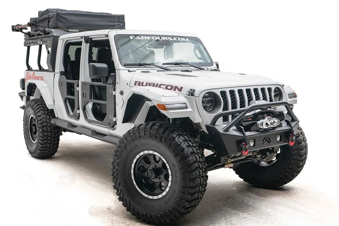 Fab Fours Stubby bumper with pre-runner guard on a white Jeep Wrangler JL, passenger-side front three-quarter view, showing the tube hoop, winch and red D-ring shackles